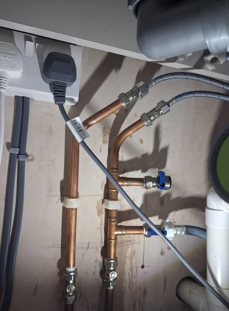 New copper pipework with blue-handled appliance valves under a worktop
