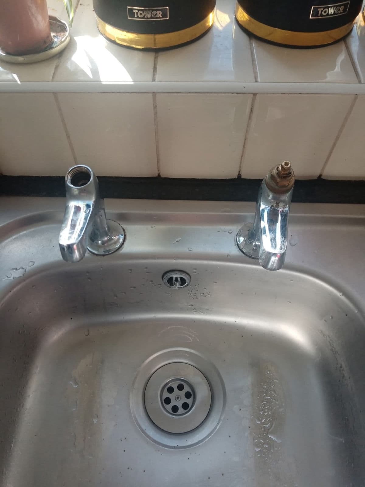 A stainless sink with two pillar taps, part way through a job