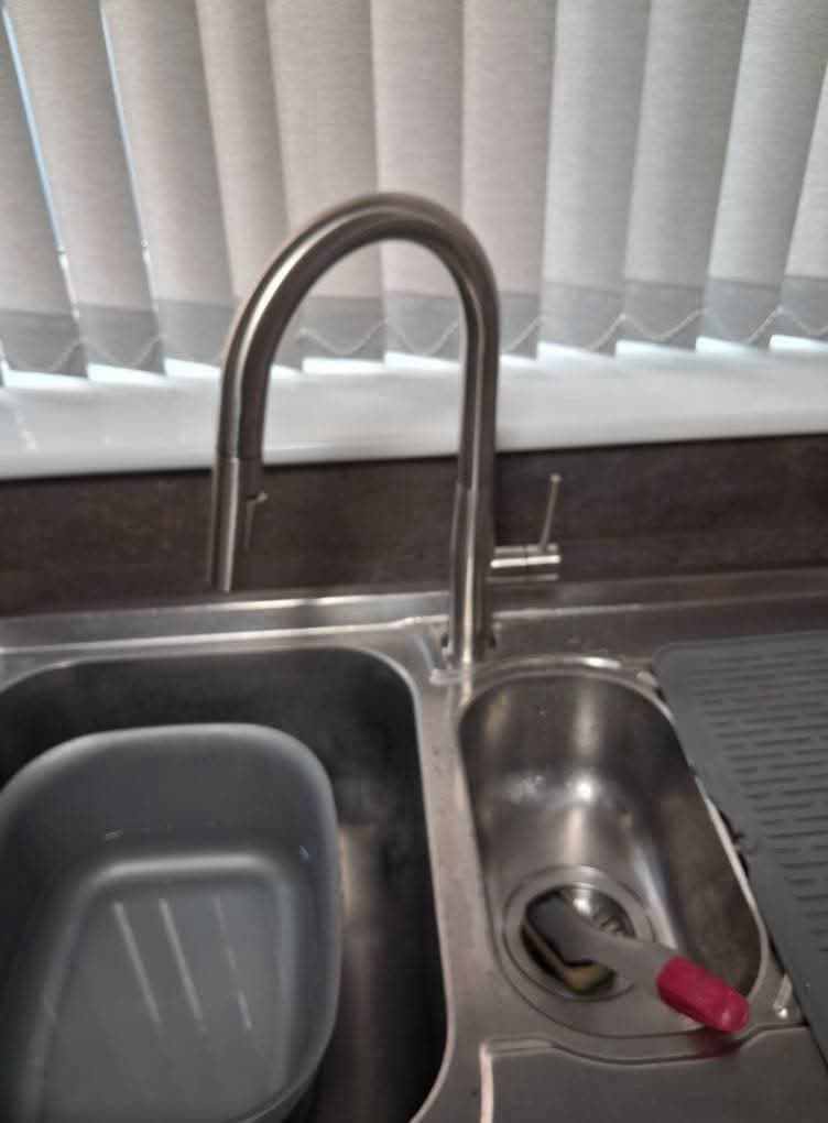 A brushed-steel kitchen mixer tap over a stainless double sink